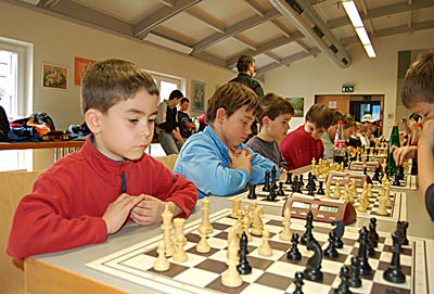 Kinder blicken angestrengt auf das Schachbrett